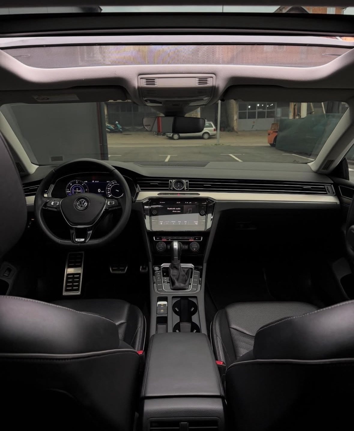 Interior view of a Volkswagen car showing dashboard, steering wheel, and windshield view of parking garage