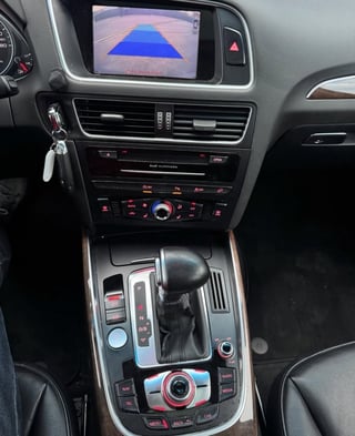 Car interior dashboard displaying backup camera feed with blue parking guidance lines on infotainment screen