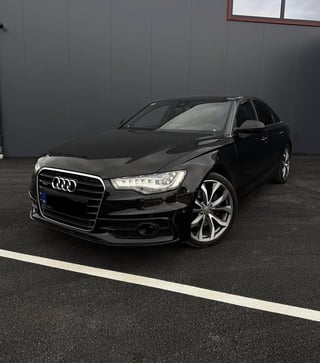 Black Audi sedan parked in indoor garage with gray walls and white parking line