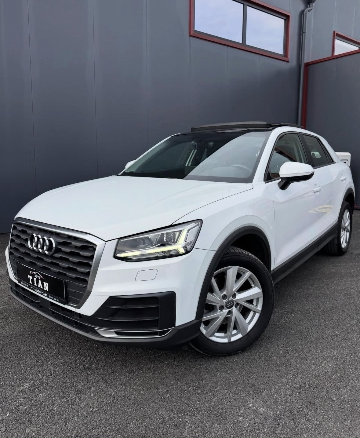 White Audi Q2 SUV parked in an indoor garage with gray walls and red-framed windows