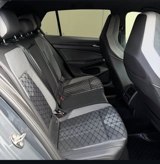 Interior view of a cars back seat with gray and white quilted upholstery and black accents