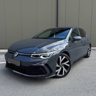 Blue Volkswagen Golf ID electric car parked in front of gray ribbed wall, angled front-left view