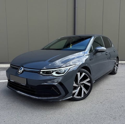 Blue Volkswagen Golf electric car parked against gray wall background