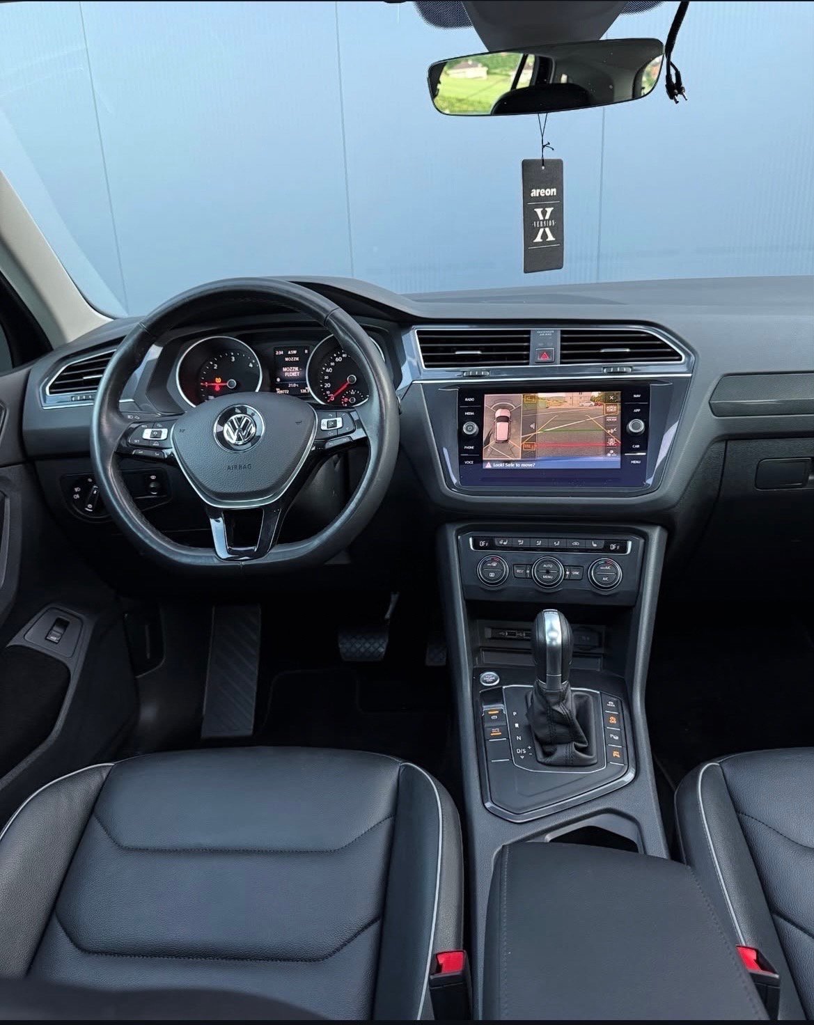 Interior view of a Volkswagen vehicle showing steering wheel, dashboard with touchscreen, and front seats from drivers perspective