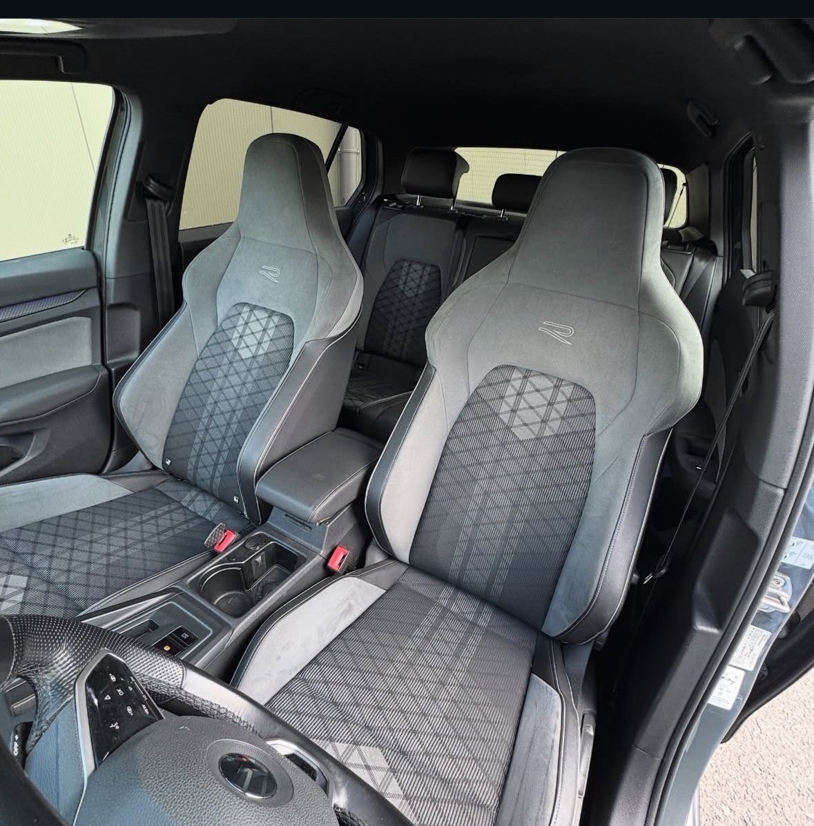 Two gray and white sport bucket seats with quilted pattern inside a vehicle interior with black trim and dashboard