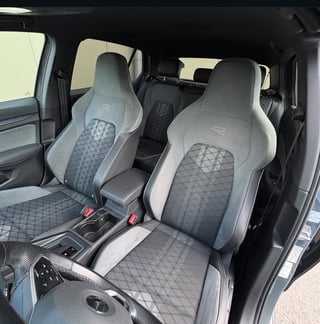 Two gray and white sport bucket seats with quilted pattern inside a vehicle interior with black trim and dashboard