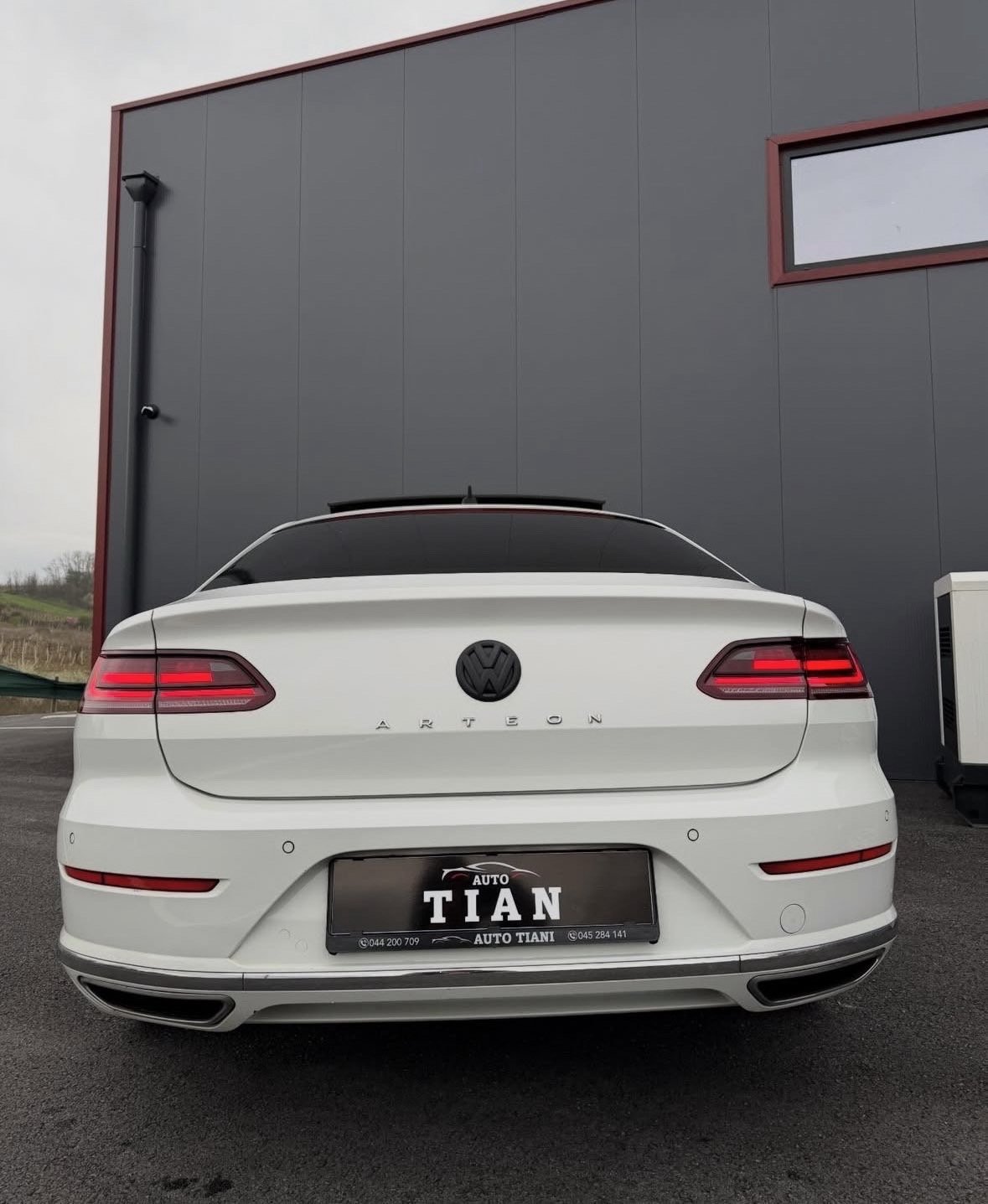Rear view of a white Volkswagen Arteon sedan with red taillights and Titan auto dealership license plate