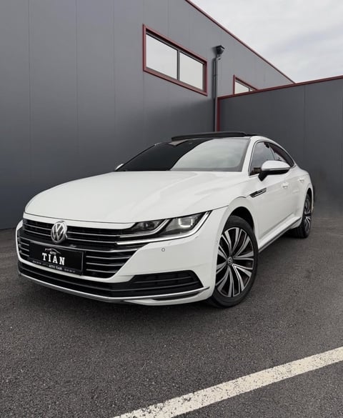 White Volkswagen Titan sedan parked in a modern industrial garage with red metal framing and windows