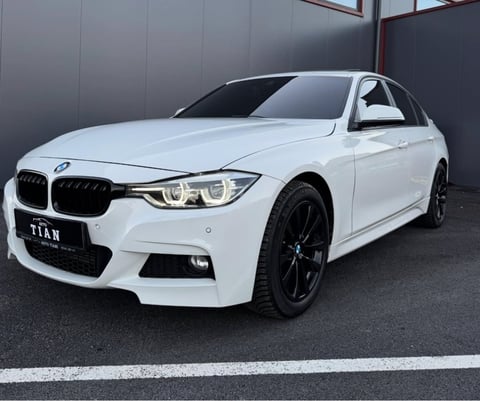 White BMW sedan with black wheels parked in front of gray wall, featuring distinctive kidney grille and LED headlights