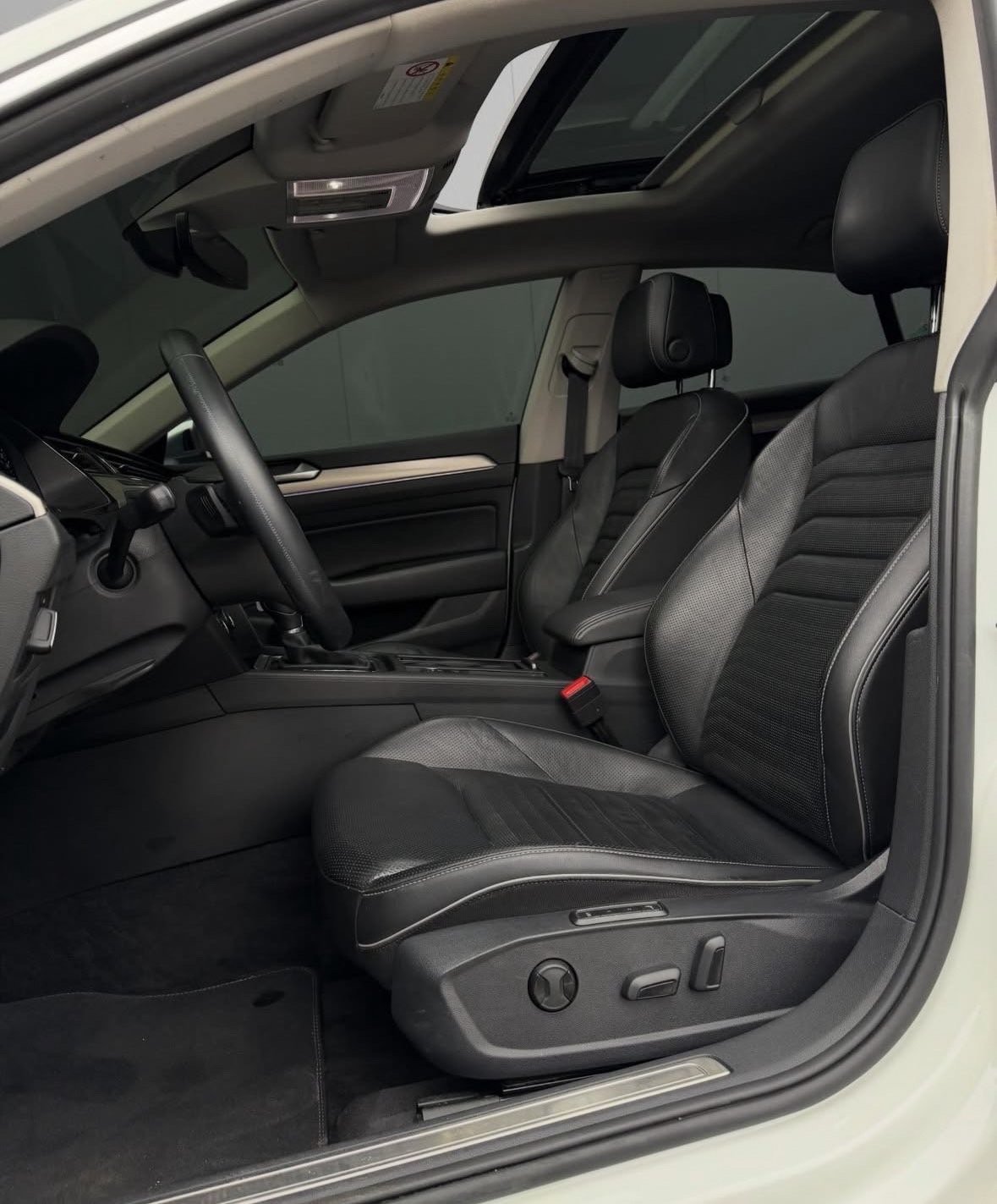 Interior of a modern white car showing black leather seats, steering wheel, and dashboard with sunroof visible