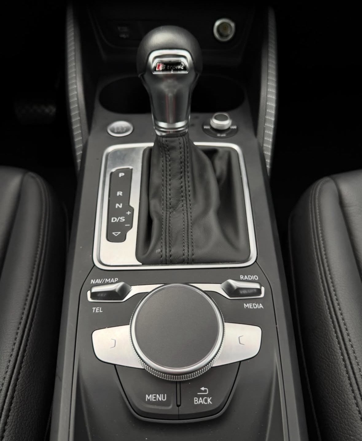 Close-up of car center console with automatic transmission shifter and infotainment control knob