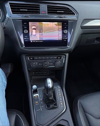 Car interior dashboard with touchscreen display showing 360-degree camera view and climate controls below