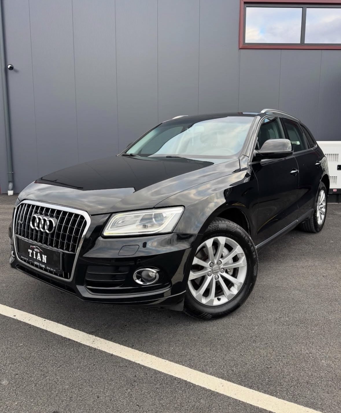 Black Audi Q5 SUV parked in a lot with white wall building