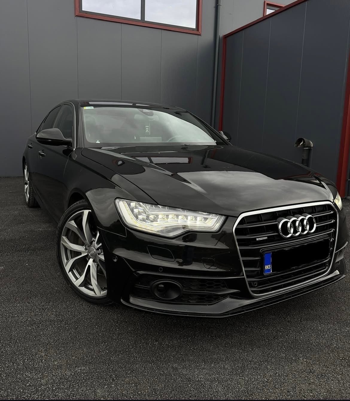 Black Audi sedan parked in garage with LED headlights and alloy wheels