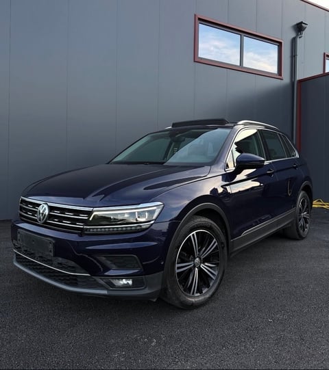 Dark blue Volkswagen SUV parked in front of a gray warehouse building with metal siding